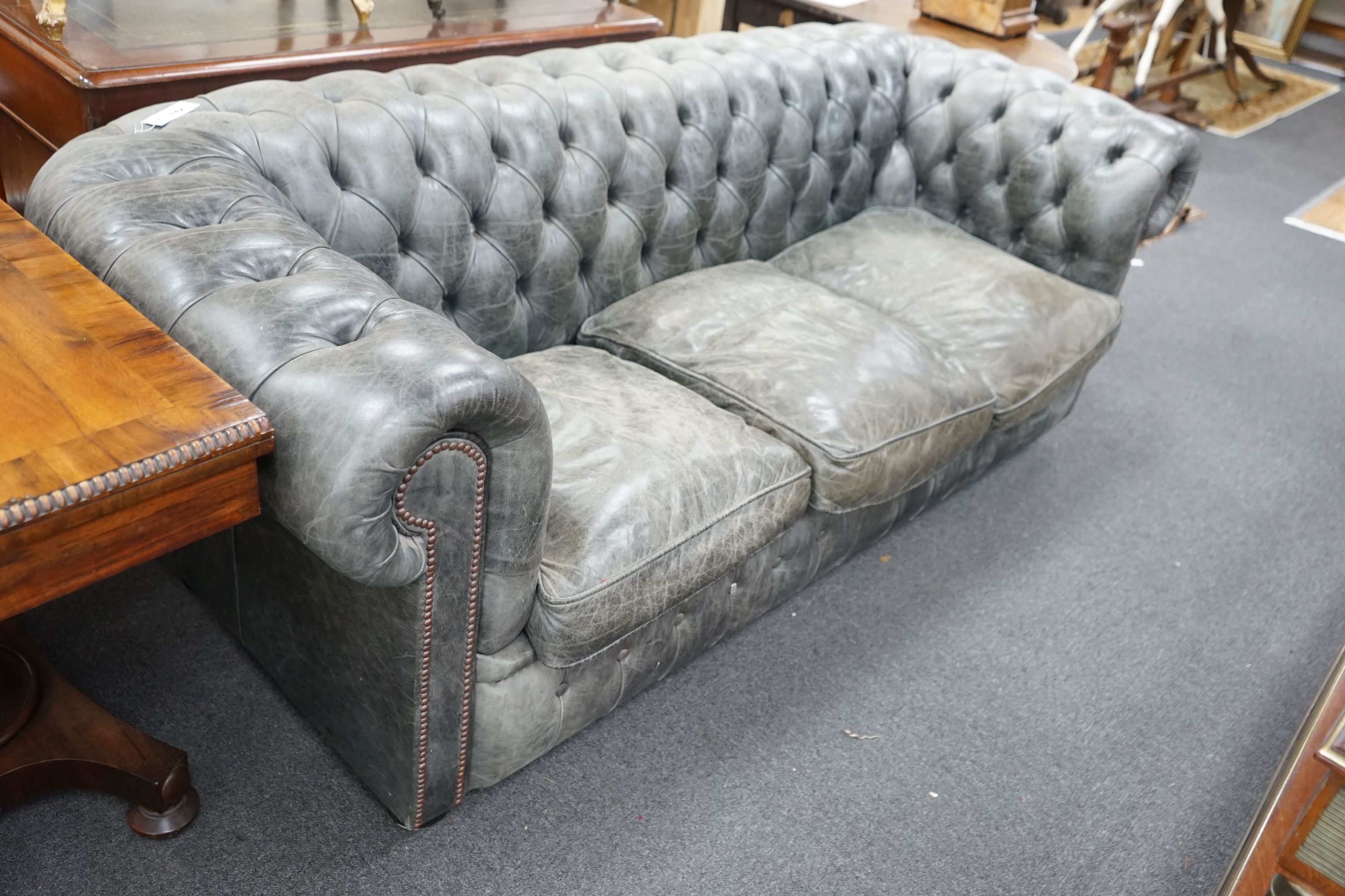 A deep buttoned faded black leather Chesterfield three seater settee, length 210cm, depth 90cm, height 78cm